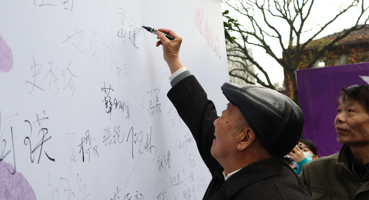 南京大屠杀幸存者葛道荣在和平寄语墙上签名。